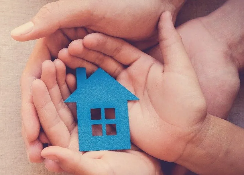 Hands holding a paper home cutout